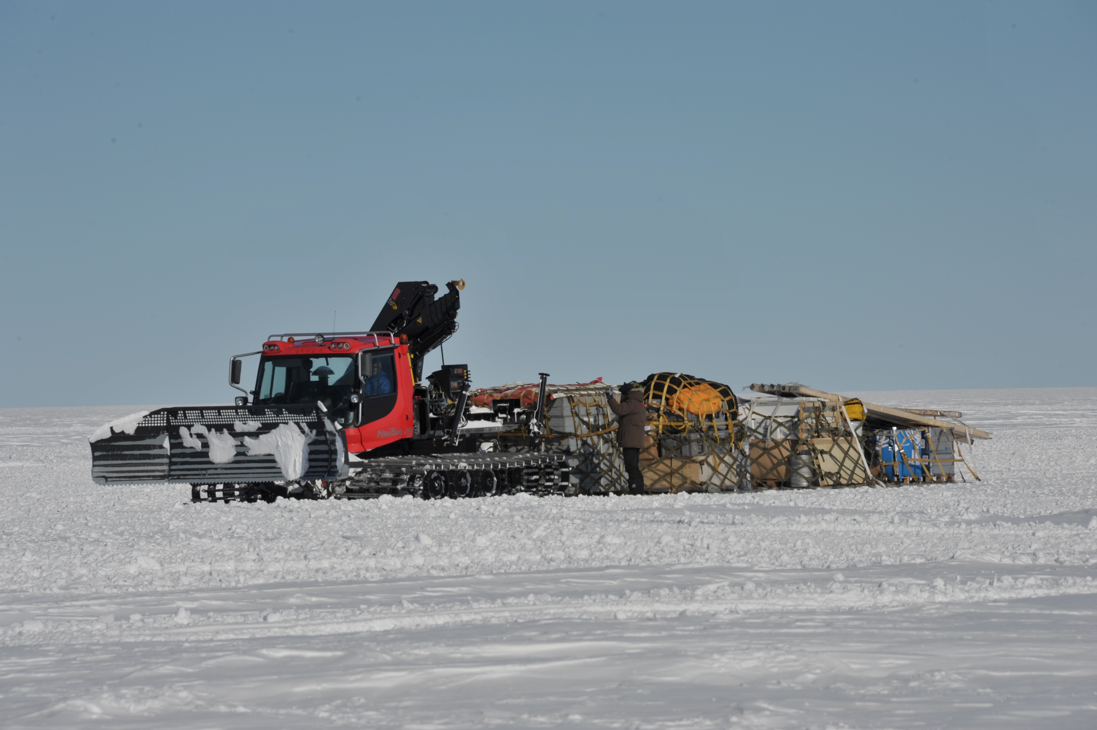 Pistenbully (pistemaskine) der trækker 4 lastpaller med nytilkommen fragt ind i lejren.