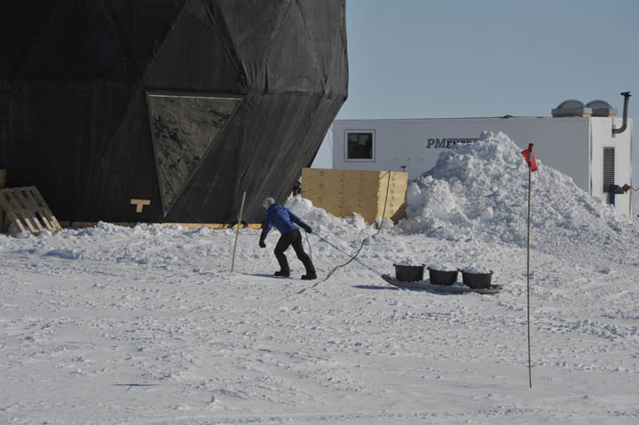 Kaitlin dragging snow from the clean snow area to the drinking water barrel